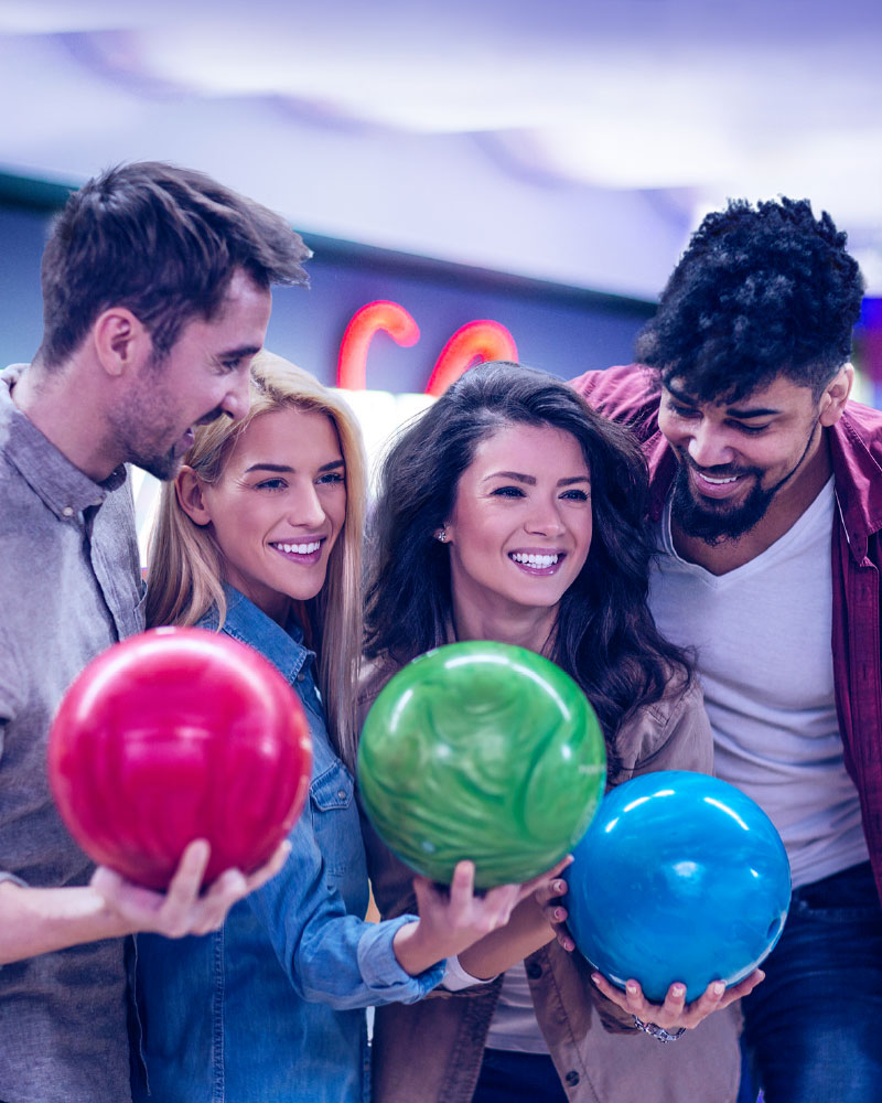 Four smiling friends holding bowling balls