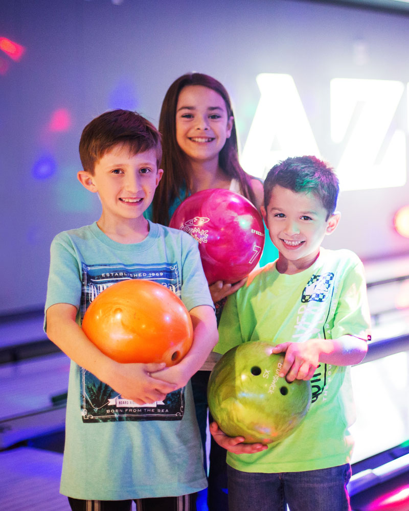 Four smiling friends holding bowling balls